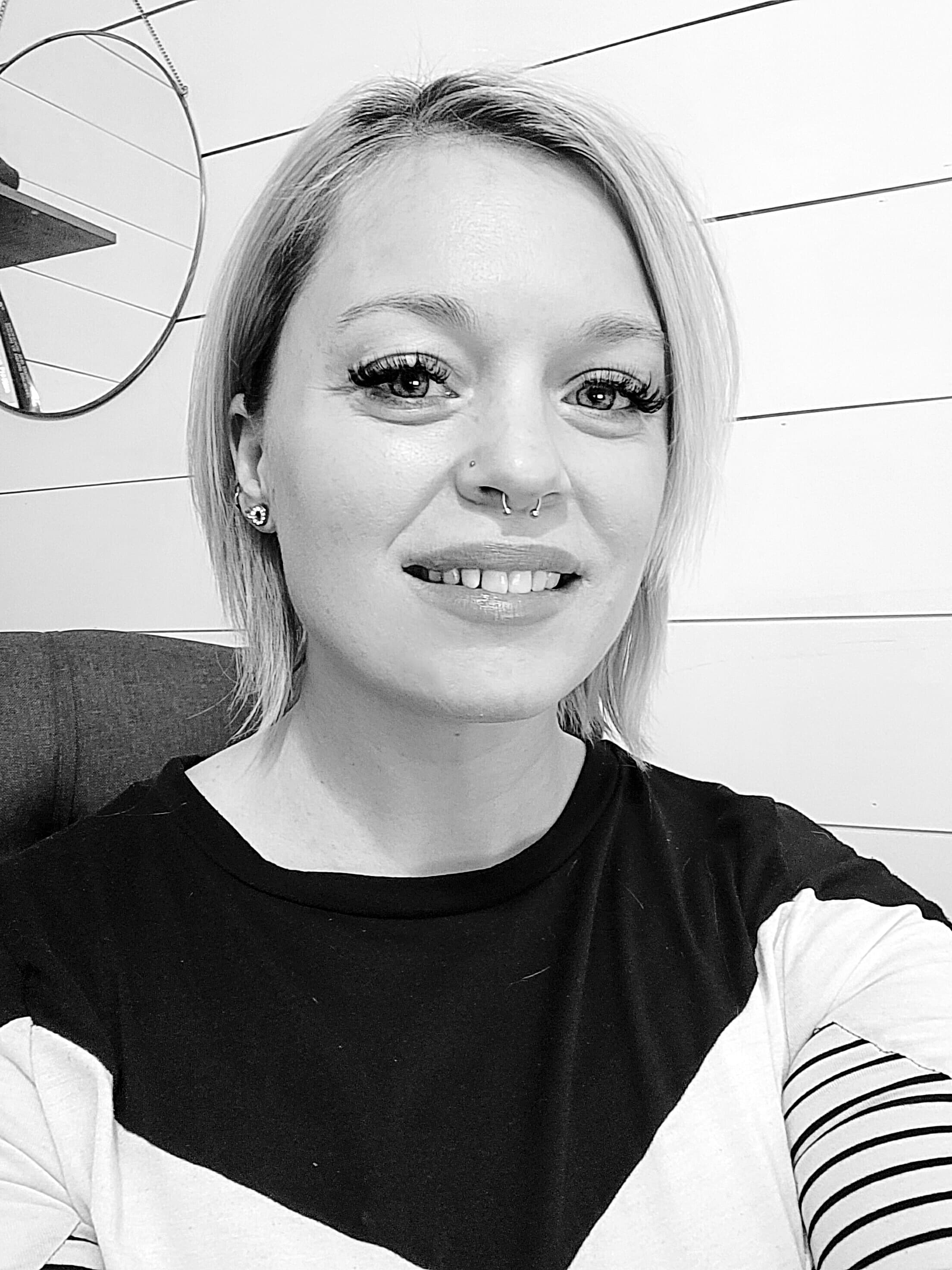 This black and white photo shows Aundria, a twenty something female with short light-colored hair. She is wearing a dark colored shirt and smiling.